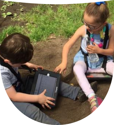 Two little kids on ground wearing their AAC devices